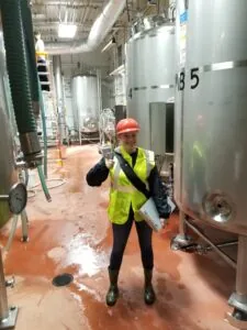 Employee in high visibility PPE standing in a facility and giving a thumbs up